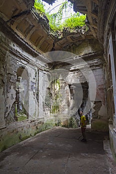 A room with a hole in the roof in old tample. Marble statue in temple in the park of the Royal Palace of Caserta, Italy. A boy is