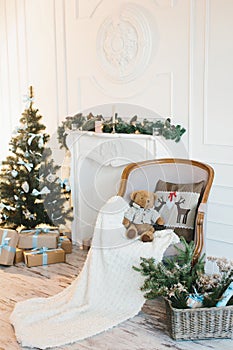 Room interior for Christmas and New Year, with a decorated Christmas tree, armchair, fireplace and candles.