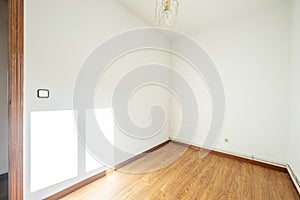 A room with lsio white painted walls, oak slat parquet flooring, outdoor heating ducts and a ceiling lamp