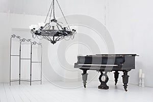 Room with a piano, folding screen and chandelier photo