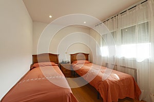 Room with two twin beds, tile-colored bedspreads, wooden headboards