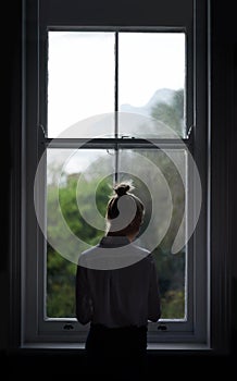 Room with a view. A beautiful young woman standing by a window.