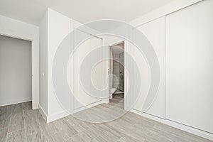 Room with white fitted wardrobes with wooden sliding doors