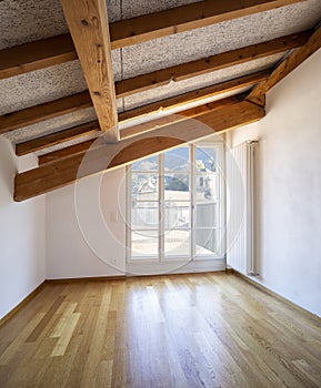 Room with wooden beams and large windows overlooking the Swiss Alps