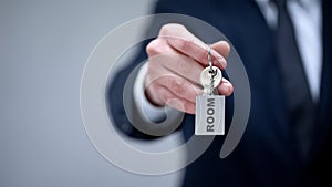 Room word on keychain in male hand, rental housing service for business trip