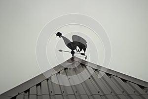 A rooster on the roof catches the wind