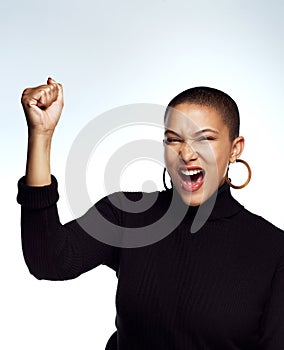 Always rooting in your corner. Studio shot of an attractive young woman posing with her arm raised and fist clinched photo
