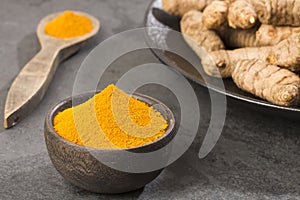 Turmeric powder and fresh turmeric on wooden background photo