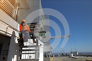 Rope access abseiler working at height installing exit sign at roof top at the emergency exit door photo