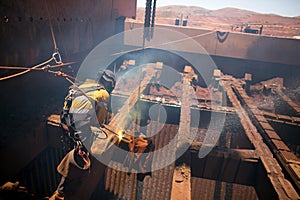 Rope access boiler maker abseiler wearing safety harness, helmet standing on beam structure using two rope in fall arrest position