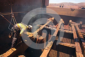 Rope access boiler maker abseiler wearing safety harness, helmet standing on beam structure using two rope in fall arrest position