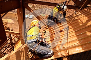 Rope access maintenance wearing safety harness, helmet abseiling with two ropes seating knee bend wearing a glove hand protection