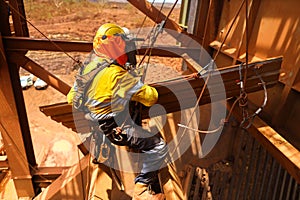 Rope access maintenance wearing safety harness, helmet abseiling with two ropes seating knee bend wearing a glove hand protection
