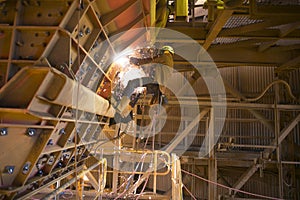 Rope access miner wearing safety harness helmet uniform working at height on rope commencing gouging photo