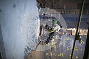 Rope access sandblaster worker wearing safety equipment harness working at height