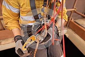 Rope access technician performing transferring his working rope from chest ascender to descender device photo