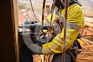Rope access technician wearing safety harness abseiling with twin rope working at height commencing electric magnet drilling