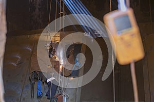 Rope access welder wearing safety equipment, harness helmet doing hot work, welding in confined space which have blurry gas test d photo