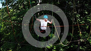 Rope adventure - man walk on the suspension rope attached to the tree