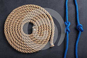 A rope coiled in a circle and two sailing knots. Accessories for sea wolves on the table