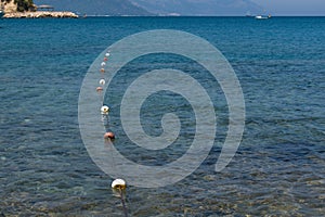 Rope with cork buoys extending into blurred background of blue sea