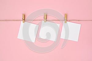 Rope with empty white paper frames with space for copy and clothespins on pink background