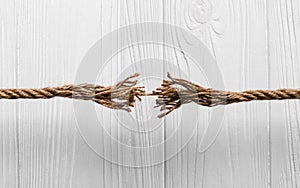 Rope frayed about to break on Wooden background