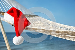 Rope hammock with Santa`s hat on beach, closeup. Christmas vacation