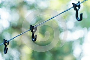 A rope with hooks for drying clothes during a hike is stretched between the trees in the forest. A tourist camp in the wild. Hooks