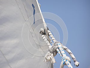 A rope on the jib of a sailboat with a blue sky as background