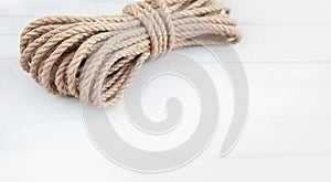 Rope made of natural jute on a white wooden background.