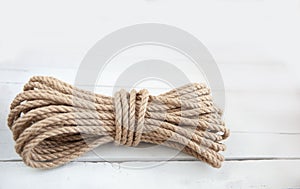 Rope made of natural jute on a white wooden background.