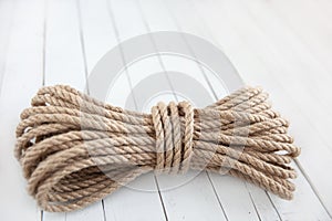 Rope made of natural jute on a white wooden background.