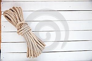 Rope made of natural jute on a white wooden background.