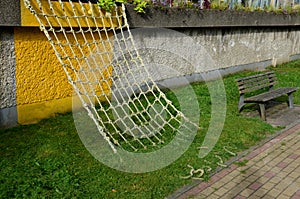 A rope net is attached to the concrete wall and is obliquely fixed to the ground. children can play sailors and test stability lik