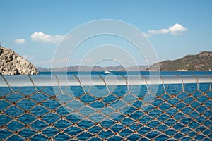 Rope net texture against blue sea background. A material net attached on safety pole that is a decoration on a yacht