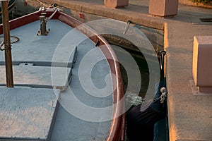 Rope and an old mooring bollard in port, up-close and in detail of the old red boat