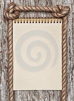 Rope, paper spiral notebook and wood background