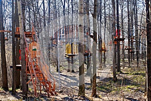 Rope park in spring forest. Wooden platforms on trees