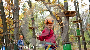 Rope Park. Two little girls in orange helmets in adventure park in safety equipment in autumn day.  Happiness and happy childhood