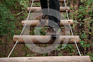 Rope park. A woman in trekking shoes runs a route in a rope park. Close-up of legs.