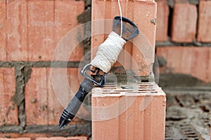 Rope plumb for even brickwork. Compliance with the correct laying of walls and corners of ceramic bricks. Bricklayer's tool