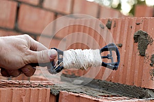 Rope plumb for even brickwork. Compliance with the correct laying of walls and corners of ceramic bricks. Bricklayer's tool