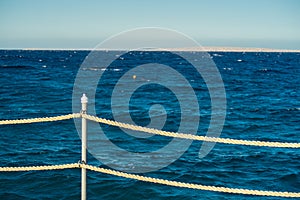 Rope railing of a landing stage in the evening light. View over the Sea