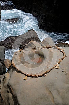 Rope and Rock at the Udo Jingu - Shinto Shrine located in Miyazaki, Japan. People throw coins into the circle for getting good luc