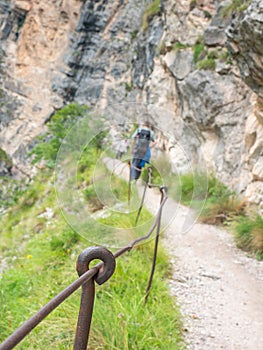 Rope and shackles anchored in hard dolomite limestone rock. Climbers path via ferrata