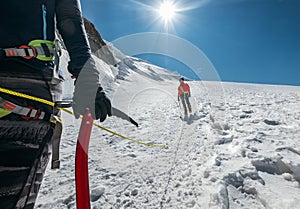 Rope team descending Mont Blanc Monte Bianco summit 4,808m dressed mountaineering clothes walking by snowy slopes with ice axe