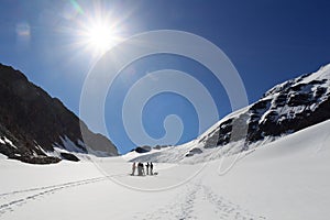 Rope team having a break on glacier Sexegertenferner and mountain snow panorama with blue sky in Tyrol Alps, Austria