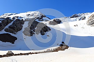 Rope team having a break on glacier Sexegertenferner and mountain snow panorama with blue sky in Tyrol Alps, Austria