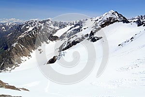 Rope team mountaineering with crampons on glacier Sexegertenferner and mountain snow panorama with blue sky in Tyrol Alps, Austria